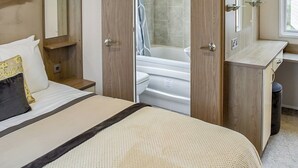 Une chambre d’hôtel avec un lit, un bureau, une salle de bain avec une baignoire et une fenêtre.