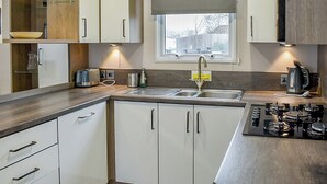 Une cuisine moderne avec des armoires blanches, un évier en acier inoxydable et une cuisinière intégrée.