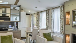 Un salon moderne comprenant un canapé, des fauteuils, une table à manger et un coin cuisine.