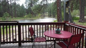 Eine Holzterrasse mit Tisch und Stühlen mit Blick auf einen Fluss und ein Waldgebiet.