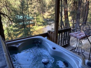 A hot tub on a wooden deck with a view of a forest. - Fabulous Mountain Chalet on the River with All the Amenities you Desire! (Garden Valley)