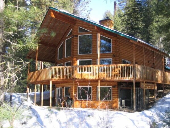 A wooden cabin with a balcony, surrounded by trees and snow. - Fabulous Mountain Chalet on the River with All the Amenities you Desire! (Garden Valley)