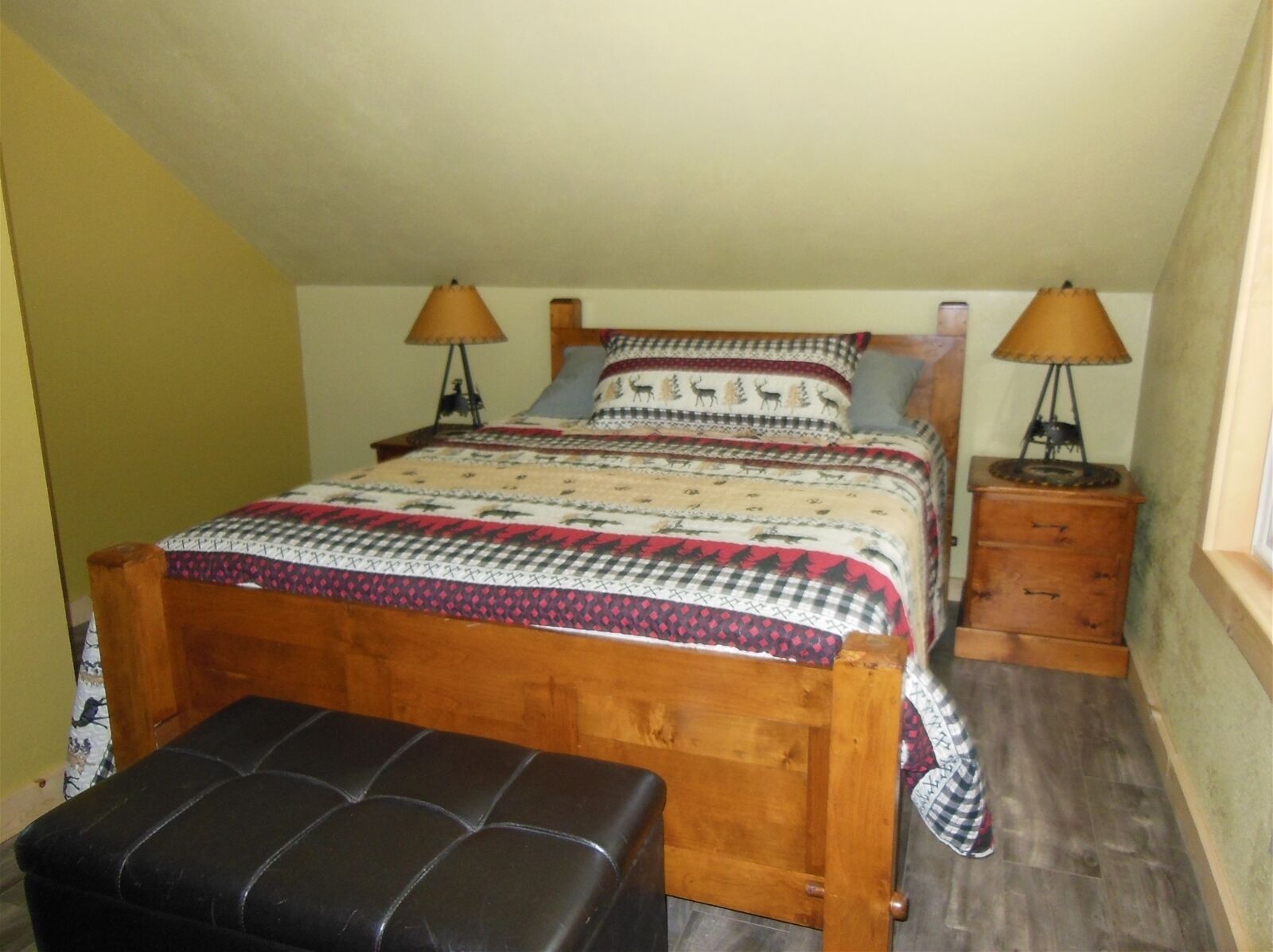 A bedroom with a wooden bed, two bedside tables, a bench, and a window.