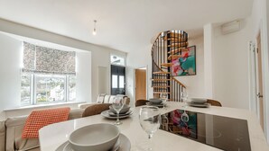 Une cuisine moderne avec un coin repas, un escalier en colimaçon et une grande fenêtre.