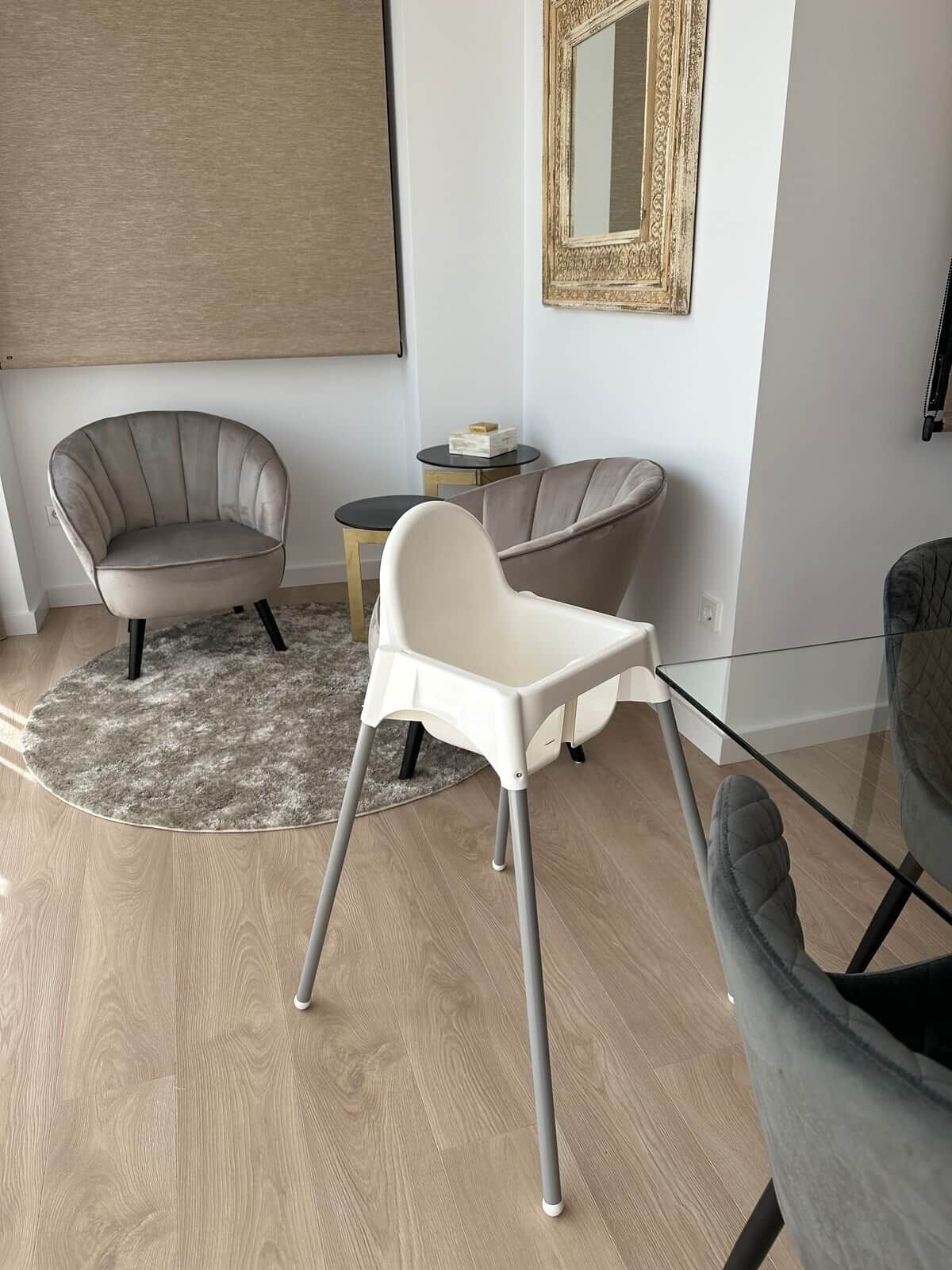 Un salon moderne avec une table basse en verre, deux fauteuils, un tapis rond et une petite table d’appoint agrémentée d’un objet décoratif.