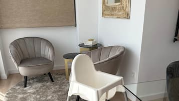 Un salon moderne avec une table basse en verre, deux fauteuils, un tapis rond et une petite table d’appoint agrémentée d’un objet décoratif.