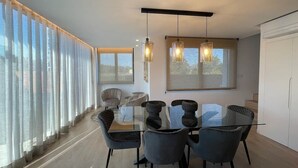 A modern dining area with a glass table, black chairs, and pendant lighting.