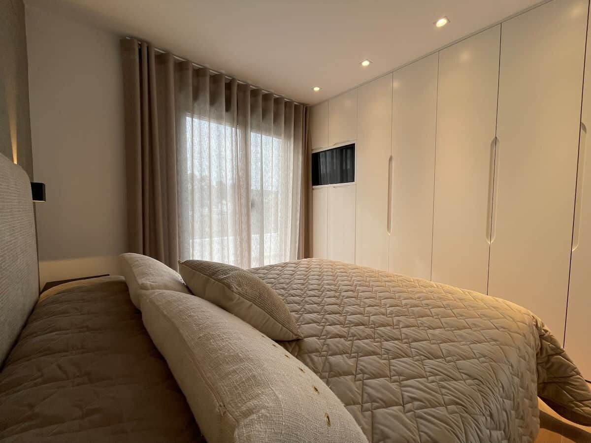 A bedroom with a bed, curtains, and a wardrobe.