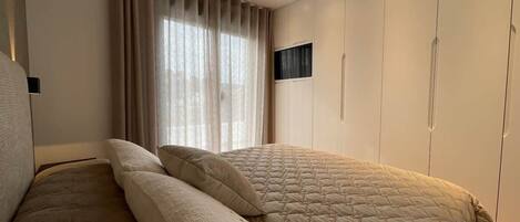 A bedroom with a bed, curtains, and a wardrobe.