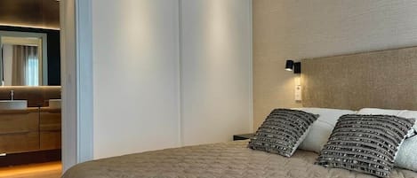 Un dormitorio con una cama grande, un armario, una mesita de noche y una lámpara de pared.