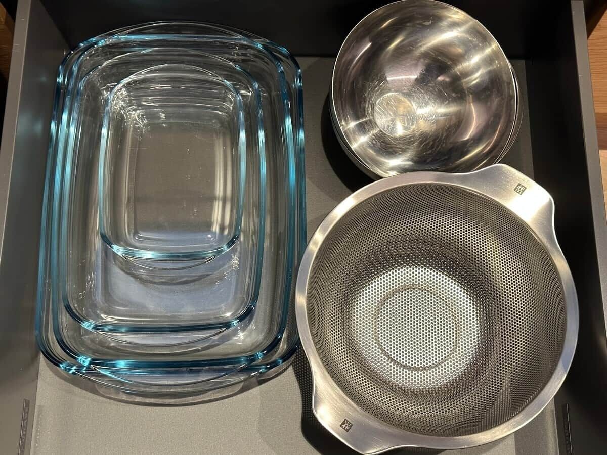 Un recipiente de vidrio transparente y un colador de metal sobre una superficie plana.