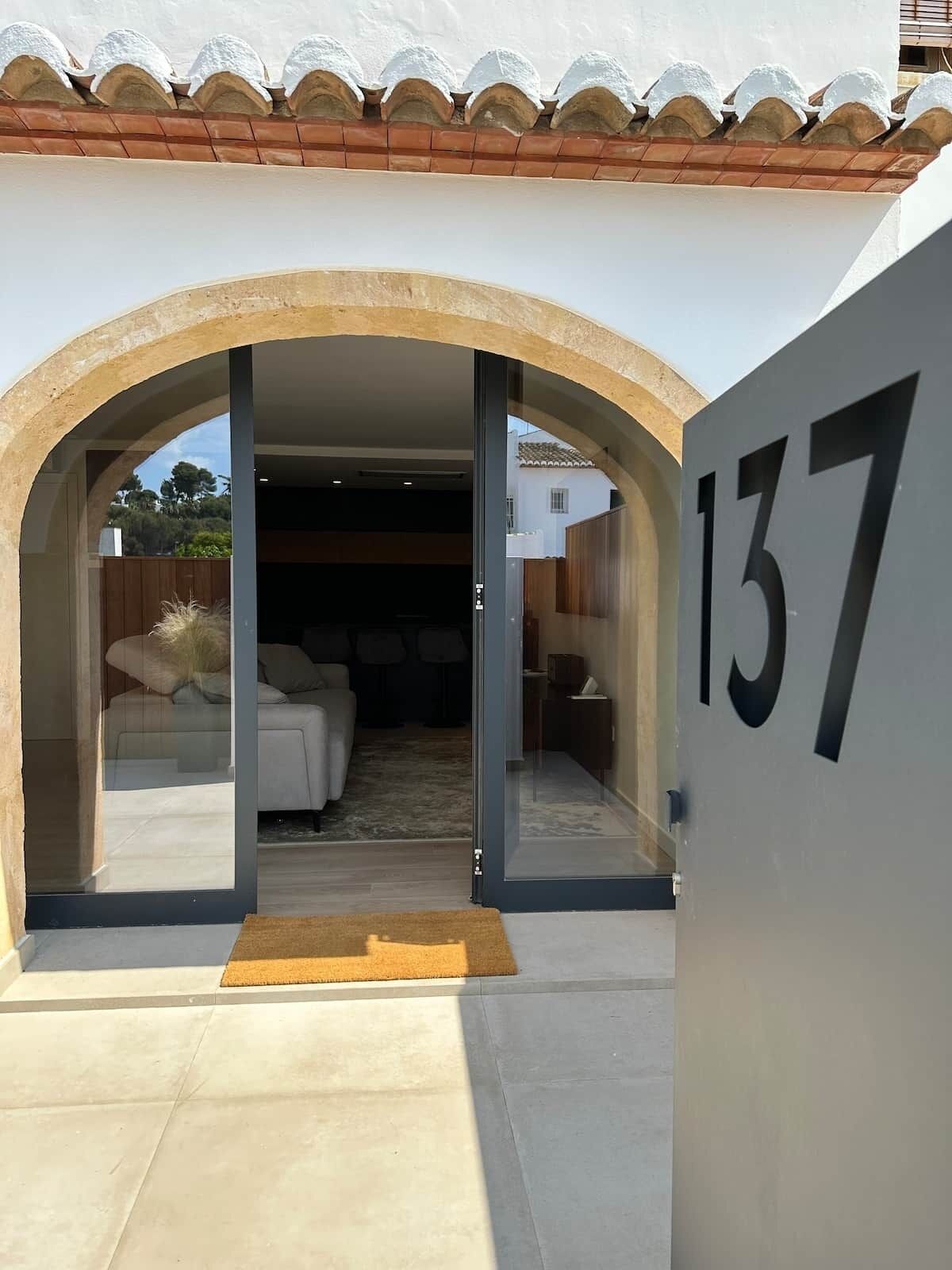 Entrada de una propiedad con un cartel con número, un arco y vista a una habitación con cama y alfombra.