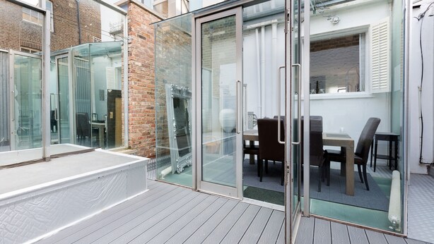 A modern outdoor patio with a glass door leading to a dining area. - Stunning flat in Notting Hill, Portobello (London)