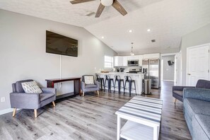 Un salon moderne avec un canapé gris, une table basse à rayures et un ventilateur de plafond.