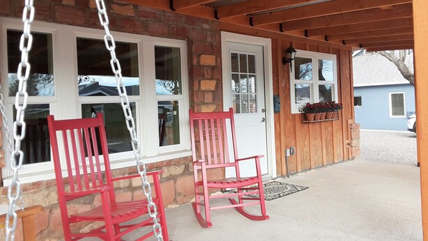 A porch with two rocking chairs and a swing.