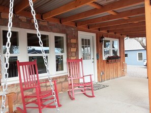 A porch with two rocking chairs and a swing.
