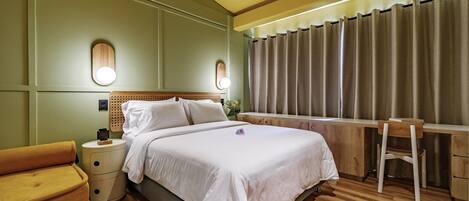 Quarto de hotel com cama, mesas de cabeceira, escrivaninha e uma cadeira.