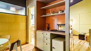 A compact kitchen with wooden cabinets, a small refrigerator, and a dining area with a table and chairs. - The Somos Flats Provenza (Medellín)