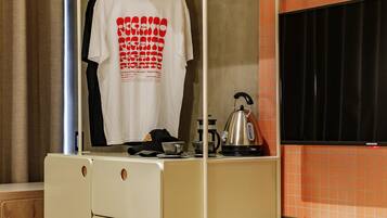 Una habitación de hotel compacta con armario, kitchenette pequeña y cama.