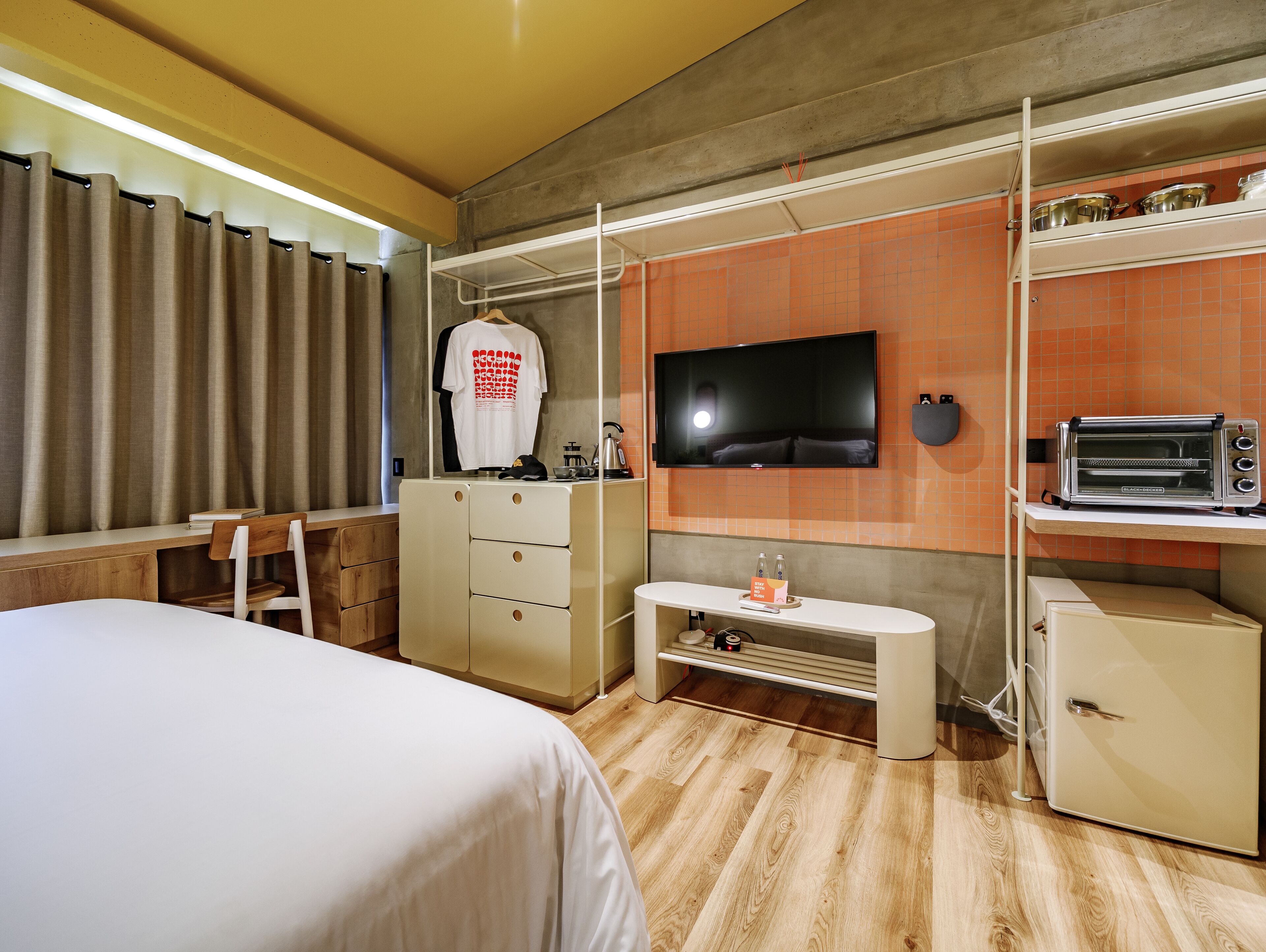 A hotel room with a bed, a desk, a TV, a mini-fridge, and a microwave.