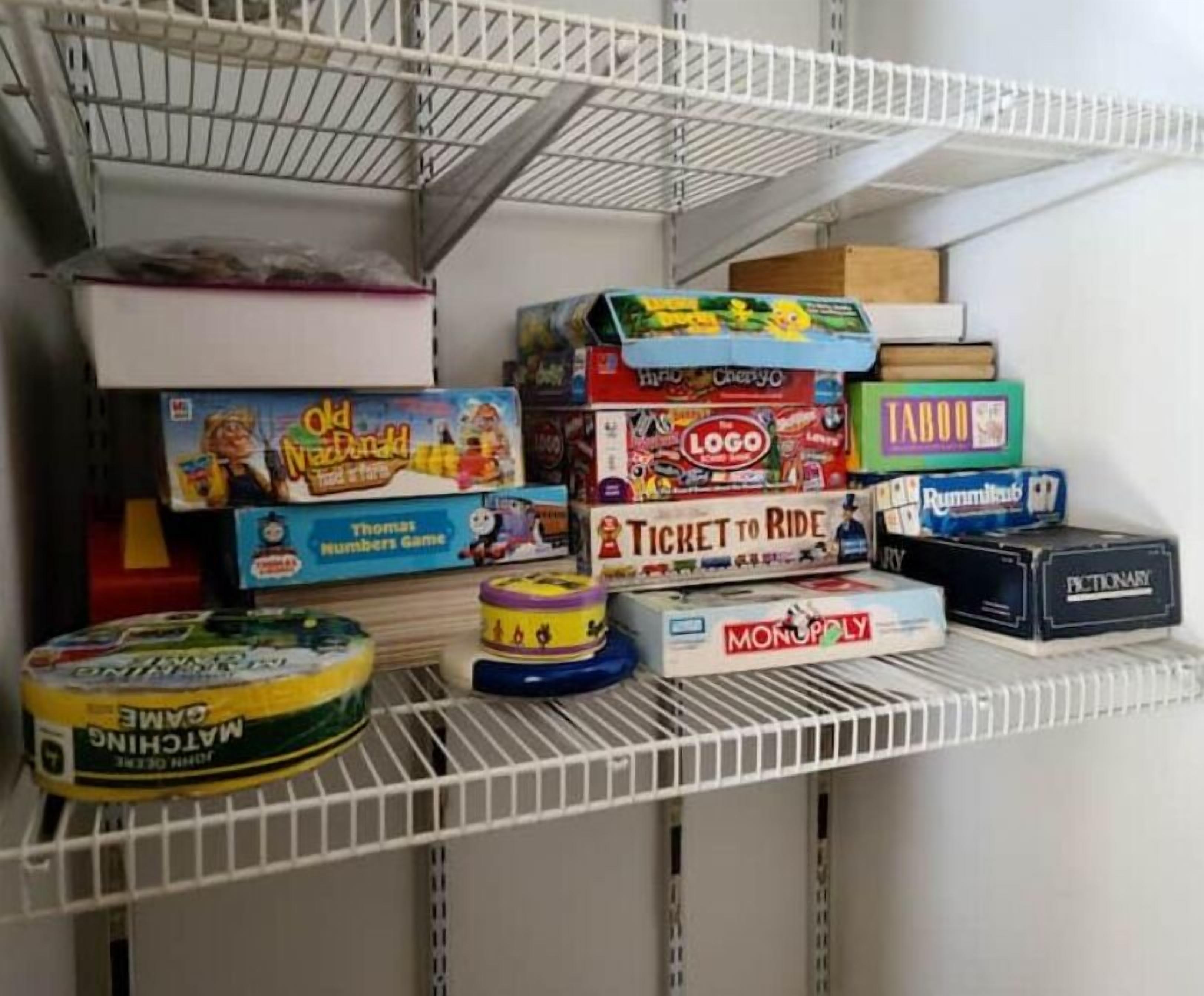A shelf with various board games including Monopoly, Ticket to Ride, and others.