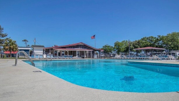 A swimming pool with lounge chairs and a pavilion. - Surf City Cozy Home · Pets Welcome · Monthly OK (Holly Ridge)