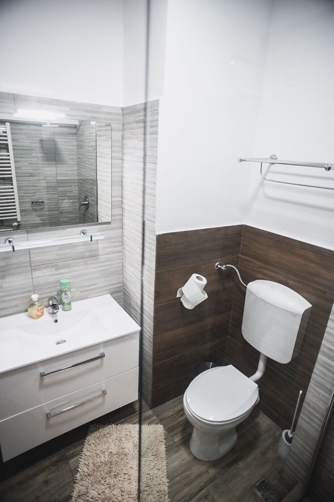 Une salle de bain moderne avec un lavabo, un miroir et des toilettes, le tout de couleur blanche.