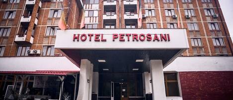 A multi-story building with a sign reading "HOTEL PETROSANI" at the entrance.