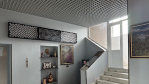 A hallway with a staircase, a decorative wall panel, and a framed landscape painting. - Petrosani Camere de Inchiriat - Hotel Petroshani srl (Petrosani)