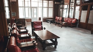 A spacious room with wooden benches and tables, large windows, and a tiled floor. - Petrosani Camere de Inchiriat - Hotel Petroshani srl (Petrosani)