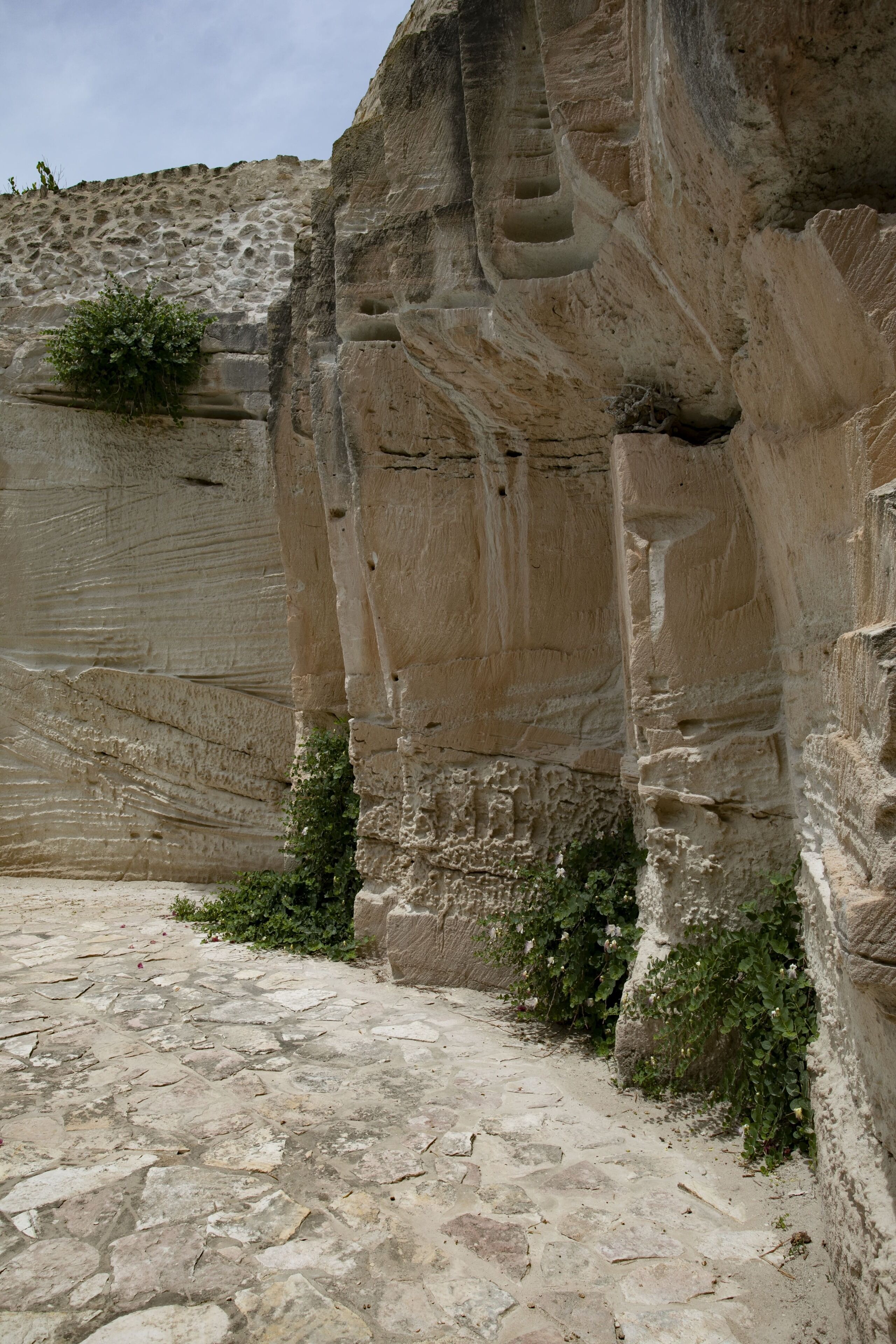 A stone pathway leading to a large rock formation with a staircase carved into it.