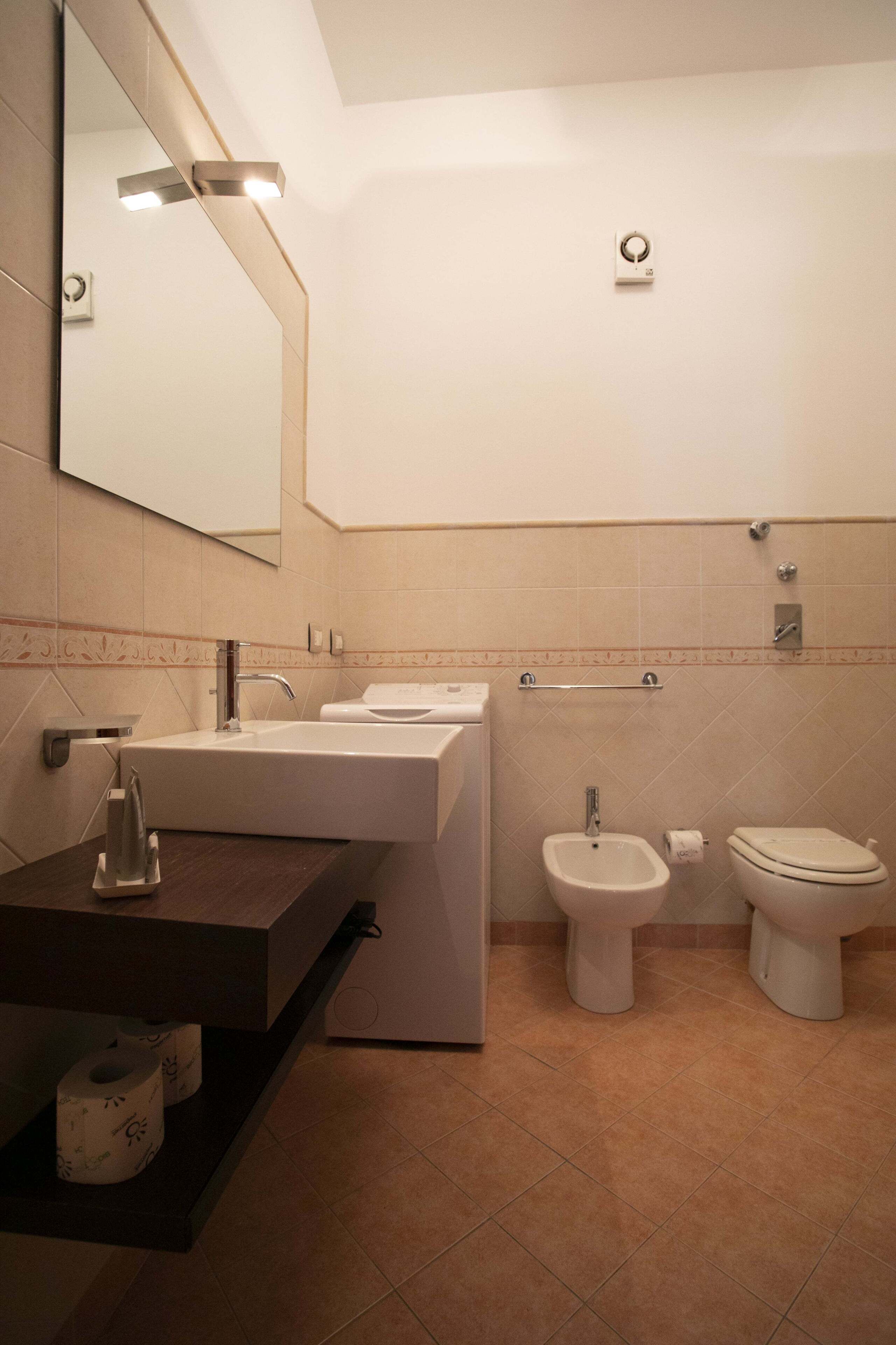 Un bagno moderno con uno specchio grande, un lavandino, un bidet e un water.