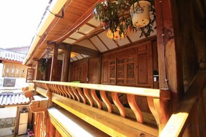 A wooden balcony with a railing, a hanging plant, and a traditional wooden door. - Yinhe Boutique Inn (Lijiang)