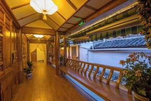 A corridor with wooden railings, potted plants, and traditional architectural elements. - Yinhe Boutique Inn (Lijiang)