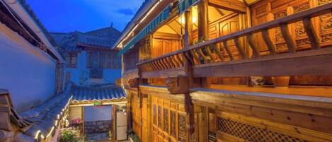 A traditional courtyard with wooden buildings, a stone pathway, and a small garden area.