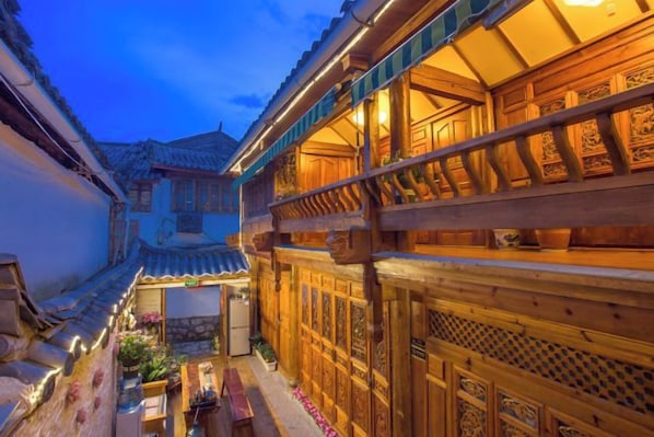 A traditional courtyard with wooden buildings, a stone pathway, and a small garden area. - Yinhe Boutique Inn (Lijiang)