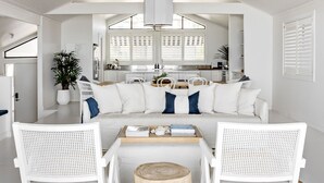 A modern, white-themed living room with a sofa, two white chairs, a coffee table, and a ceiling fan. - The Palm House Gerroa (Gerroa)