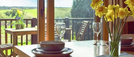 A dining table with plates, a wine glass, and a vase with flowers.
