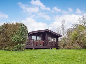 Une cabane en bois dotée d’un balcon, entourée de verdure.