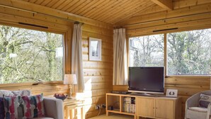 A log cabin interior with a television, wooden furniture, and large windows. - 3 bedroom accommodation in Porthgain, near St David&rsquo;s (Porthgain, near St David&rsquo;s)