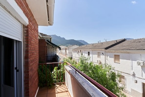 Un balcón residencial con vistas a edificios vecinos y una montaña al fondo.
