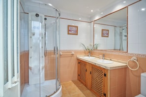 A bathroom with a glass-enclosed shower, a sink with a marble countertop, and a large mirror.