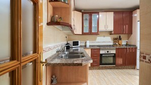 Eine Küche mit Holzausstattung, einer Granitarbeitsplatte, einer Mikrowelle und einem Spülbecken.