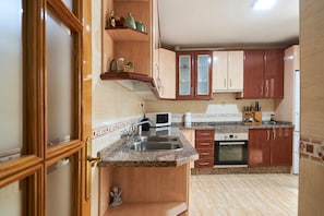 A kitchen with wooden cabinets, a granite countertop, a microwave, and a sink.