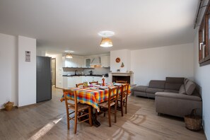A dining area with a table set for four, a sofa, and a kitchen in the background.