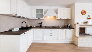 Una cocina moderna con muebles blancos, estufa a gas y horno empotrado.