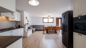 Una cocina moderna con armarios blancos, un refrigerador negro y un comedor con una mesa y sillas.