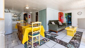 Una habitación con una mesa de comedor, sillas, un sofá, una mesa baja y una alfombra estampada.