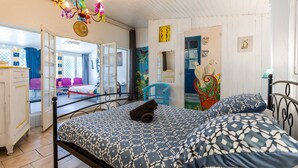 A bedroom with a bed, a chandelier, and a door leading to another room.