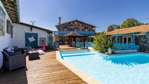 A pool area with a wooden deck, lounge chairs, and a colorful mural on the building.